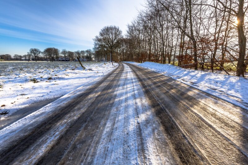 glatte leere Straße im Winter überfroren mit Eis und Schnee