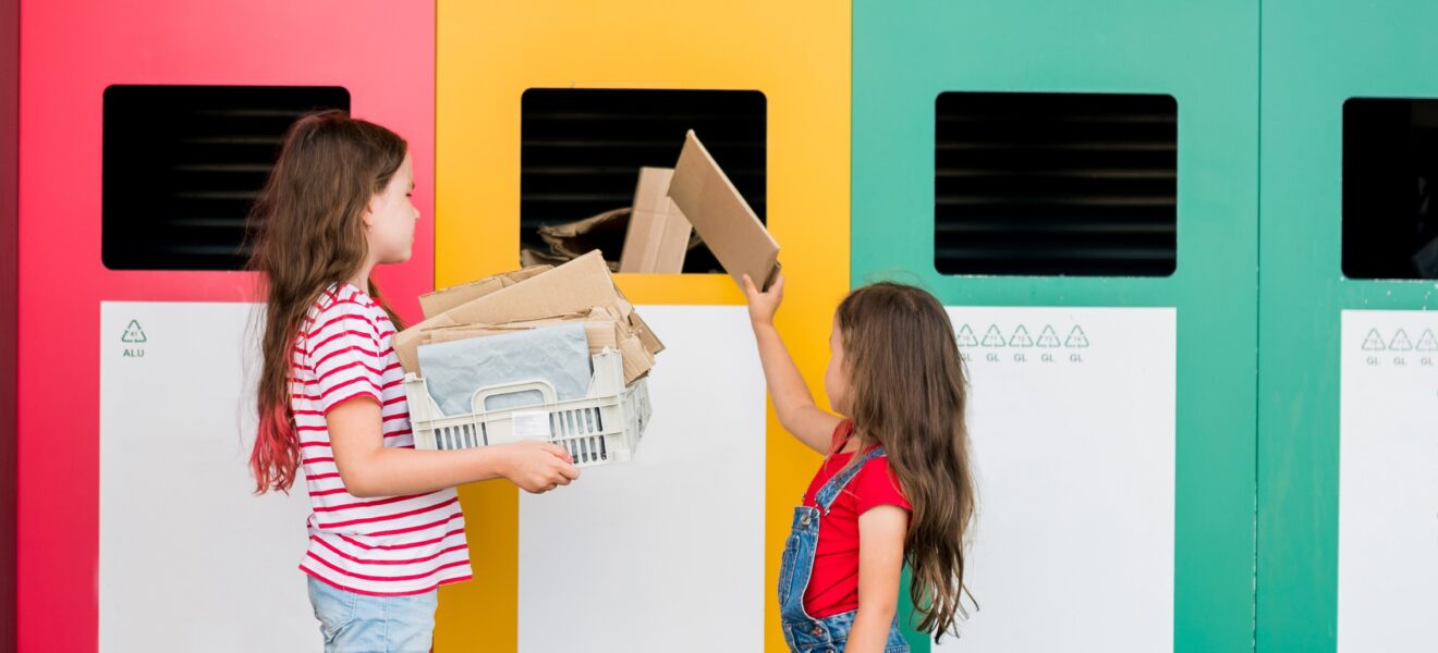 Mädchen recyceln Papier in bunte Mülltonnen