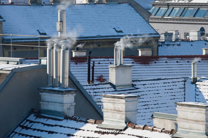 Häuserdächer im Winter mit rauchendem Schornstein