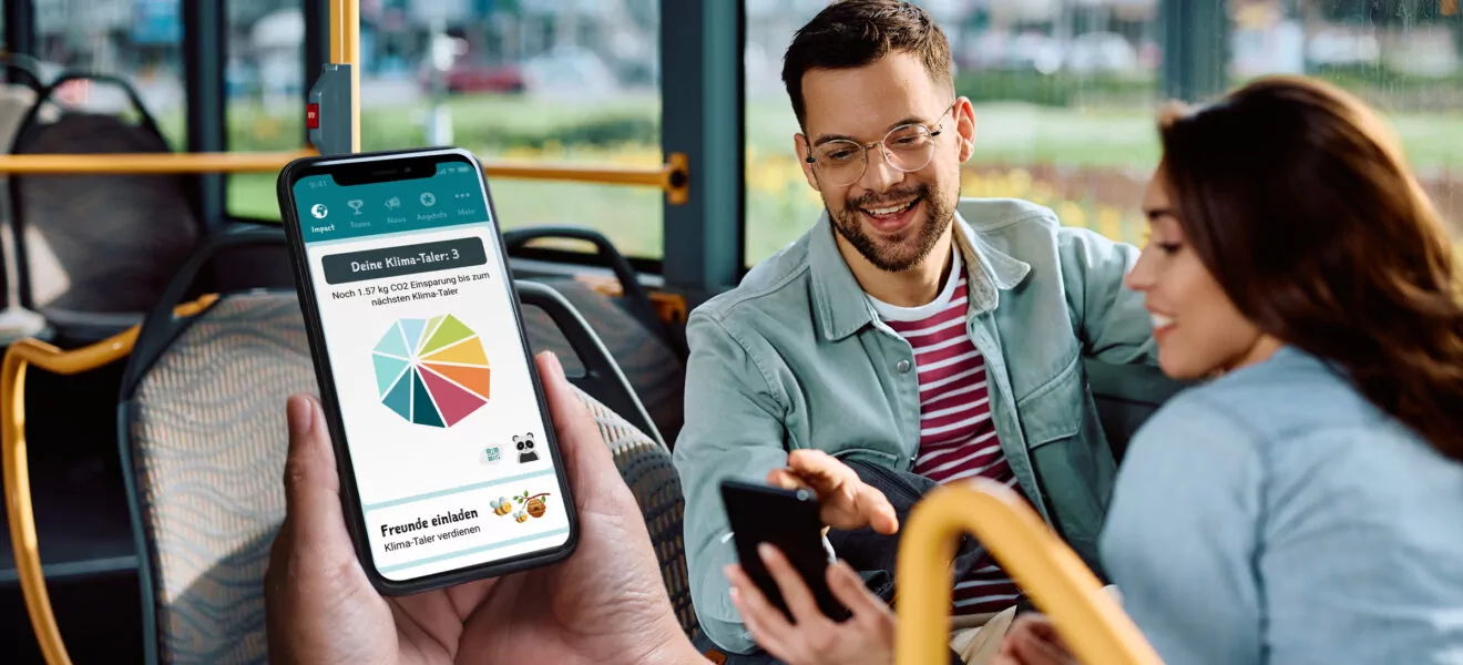 Hände halten Smartphone mit Klima-Taler-App im ÖPNV